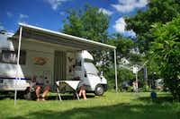 Camping L'Isle Verte - Camper sitzen vor dem Wohnmobil im Schatten der Markise