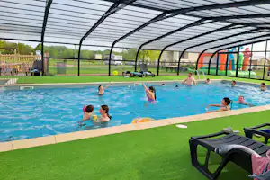 Camping Loire et Châteaux - überdachter Pool, umgeben von Kunstrasen und Liegestühlen