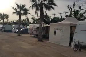 Campingplatz mit weißen Zelten und Wohnwagen, Reihe entlang des Weges, Palmen im Hintergrund.