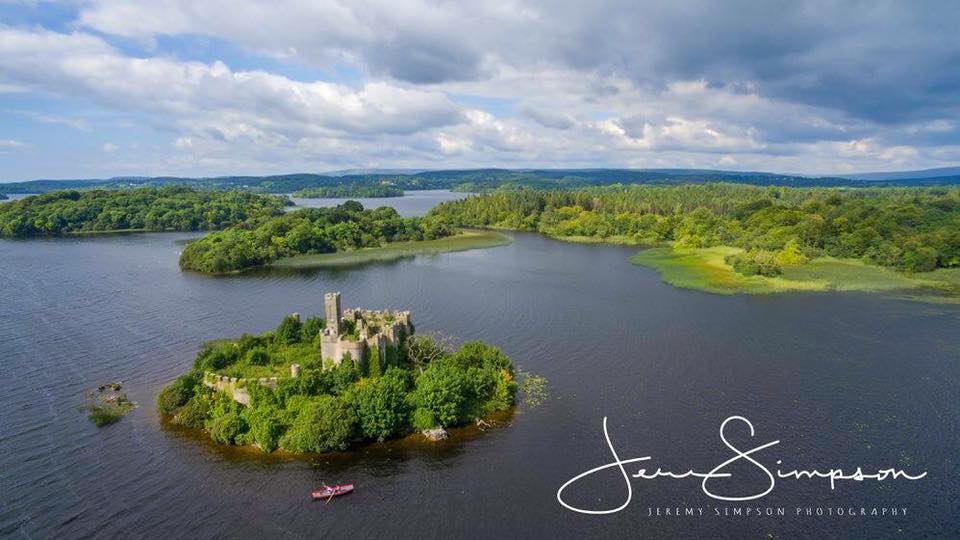Eine kleine bewaldete Insel mit Burganlage im Fluss, umgeben von Wasser und grünen Ufern.
