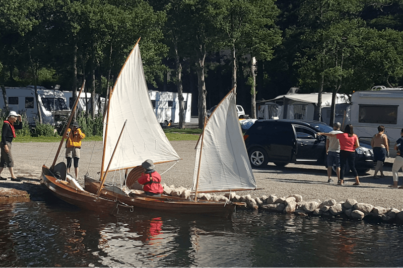 Camping Lough Ree - Camper lassen kleine Holzsegelboote zu Wasser mit Wohnwagen im Hintergrund