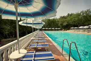 Camping Luxor Quies - Pool mit Liegestühlen umringt von Wald auf dem Campingplatz