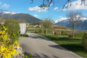 Wohnmobil auf Stellplatz am Campingplatz, Kiesweg und Rasen, Blick ins Tal mit Bergen und Bäumen im Vordergrund.