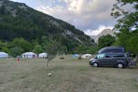 Camping Mandala - Stellplätze auf der Wiese mit Bergen im Hintergrund