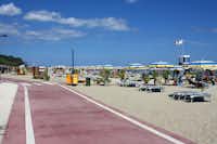 Camping Marinella  - Strand vom Campingplatz am Mittelmeer mit Sonnenschirmen und Liegestühlen