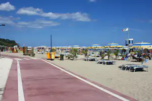 Camping Marinella - Strand vom Campingplatz am Mittelmeer mit Sonnenschirmen und Liegestühlen