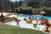 Camping Mas de Champel - Poolbereich mit Liegestühlen und Sonnenschirmen