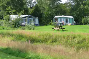 Camping Meistershof - Camperpaar vor ihrem Wohnwagen in der Sonne