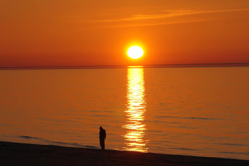 Camping Miķeļbāka - Person am Strand mit Sonnenuntergang im Rücken