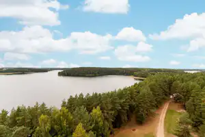 Blick auf einen See mit Wald und einem schmalen Weg am Ufer, Campingplatz in der Natur.