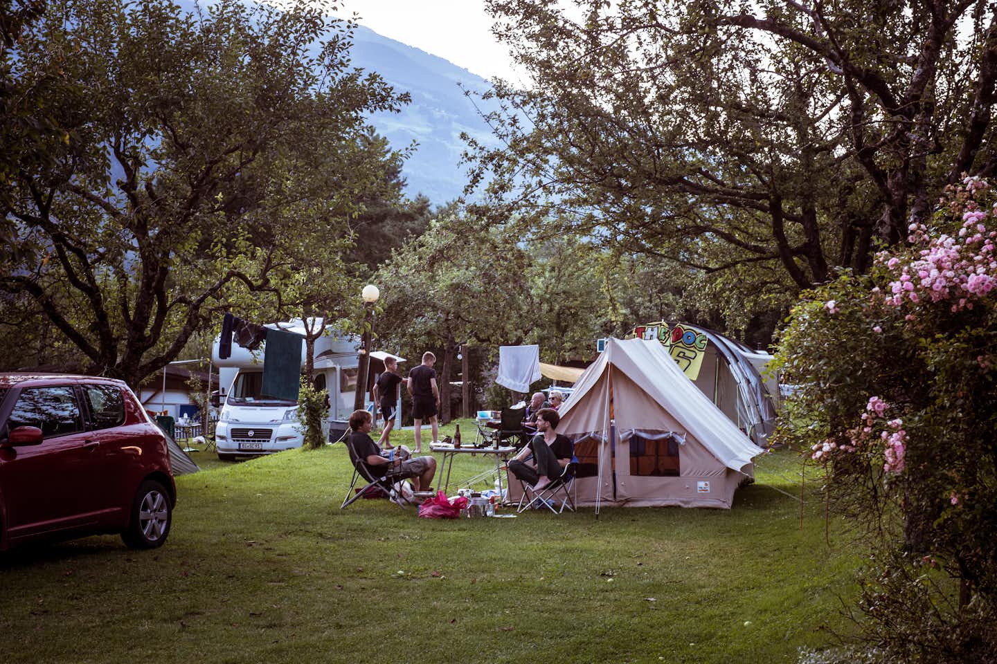Camping Mittagsspitze - Camper sitzen vor ihrem Zelt im Grünen auf dem Campingplatz