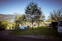 Camping Mittagsspitze - Wohnwagen und Zelte auf der Stellplatzwiese mit den Bergen im Hintergrund