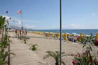 Camping Mokambo - Der Strand des Mittelmeers mit Liegestühlen und Sonnenschirmen direkt am Campingplatz