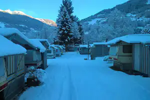 Camping Montafon - Wohnwagen mit Holzvorbauten auf dem Campingplatz im Winter