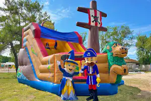 Bunte Hüpfburg mit Piraten- und Nussknacker-Motiven im Freien, daneben Bäume und ein Zaun.