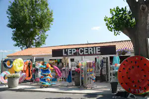 Camping-Shop „L’EP CERIE“ mit Deko und Verkaufsständen, Sonnenschirmen und bunten Schwimmringen vor dem Eingang.