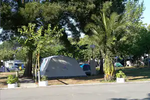 Campingzelt zwischen Bäumen am Stellplatz, mit Einfassung aus Holz und mehreren Zelten im Hintergrund.
