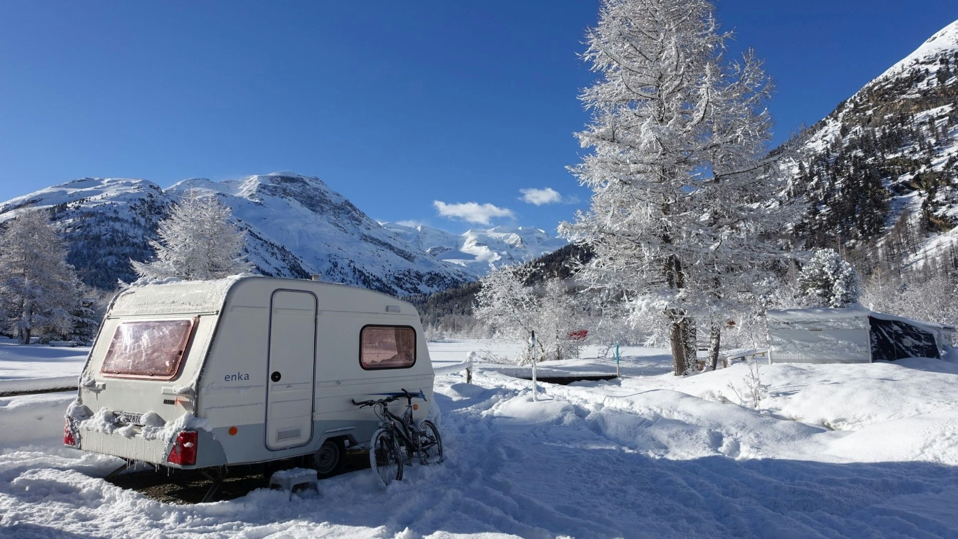 Camping Morteratsch - Wohnmobil im Schnee  mit Blick auf die Berge auf dem Campingplatz