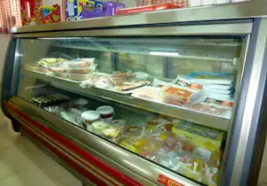 Kühlvitrine mit Lebensmitteln und Snacks, sichtbar in mehreren Fächern, mit Glastür und Edelstahlrahmen.