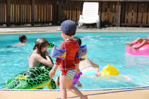 Camping Namasté - spielende Kinder im Pool vom Campingplatz mit Liegestühlen in der Sonne
