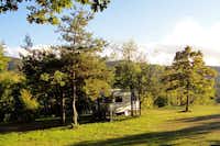 Camping Naturista Costalunga - Wohnwagen unter Bäumen auf einem Stellplatz