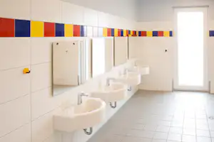 Reihe weißer Waschbecken im hellen Camping-Badezimmer mit Fliesenboden, Spiegeln und farbigen Wandpaneelen.