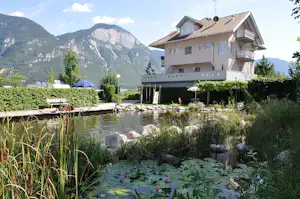 Schwimmteich mit Gebaude und Gebirge im Hintegrund auf dem Campingplatz Camping Obstgarten an der Südtiroler Weinstraße