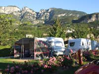 Wohnwagen- und Wohnmobilstellplätze auf der Wiese des Campingplatzes Camping Obstgarten an der Südtiroler Weinstraße mit Gebirge im Hintergrund
