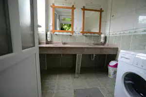 Camping Oliva - Sanitärbereich vom Campingplatz mit Waschbecken, Waschmaschine und Spiegeln