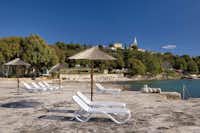 Camping Orsera  -  Strand vom Campingplatz mit Sonnenschirmen und Liegestühlen