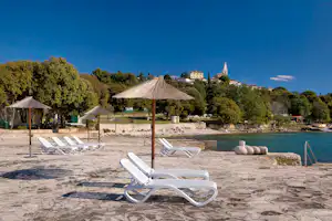 Camping Orsera - Strand vom Campingplatz mit Sonnenschirmen und Liegestühlen