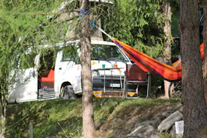 Camping Pè da Munt - Campingbulli und zwischen Bäumen aufgespannte Hängematte