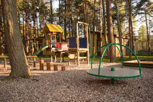 Camping Pajūrio - der Kinderspielplatz mit Kletterburg vor Campingbungalows