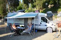 Camping Panoramico - Camper sitzen unter der Markise ihres Wohnmobils