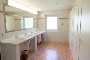 Camping Passrucker - Innenraum des Sanitärgebäudes mit Toilettenkabinen, Waschbecken und Spiegeln
