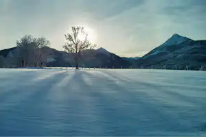 Camping Passrucker - Wiese des Campingplatzes im Winter mit den Bergen im Hintergrund