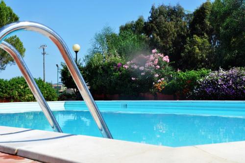 Campingpool mit Treppe aus Metall, umgeben von Blumenbeeten und Bäumen im Hintergrund.