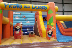Aufblasbares Piraten-Spielgerät für Kinder mit Rutsche, Meer- und Piratenmotiven, vor einer Gebäudewand.