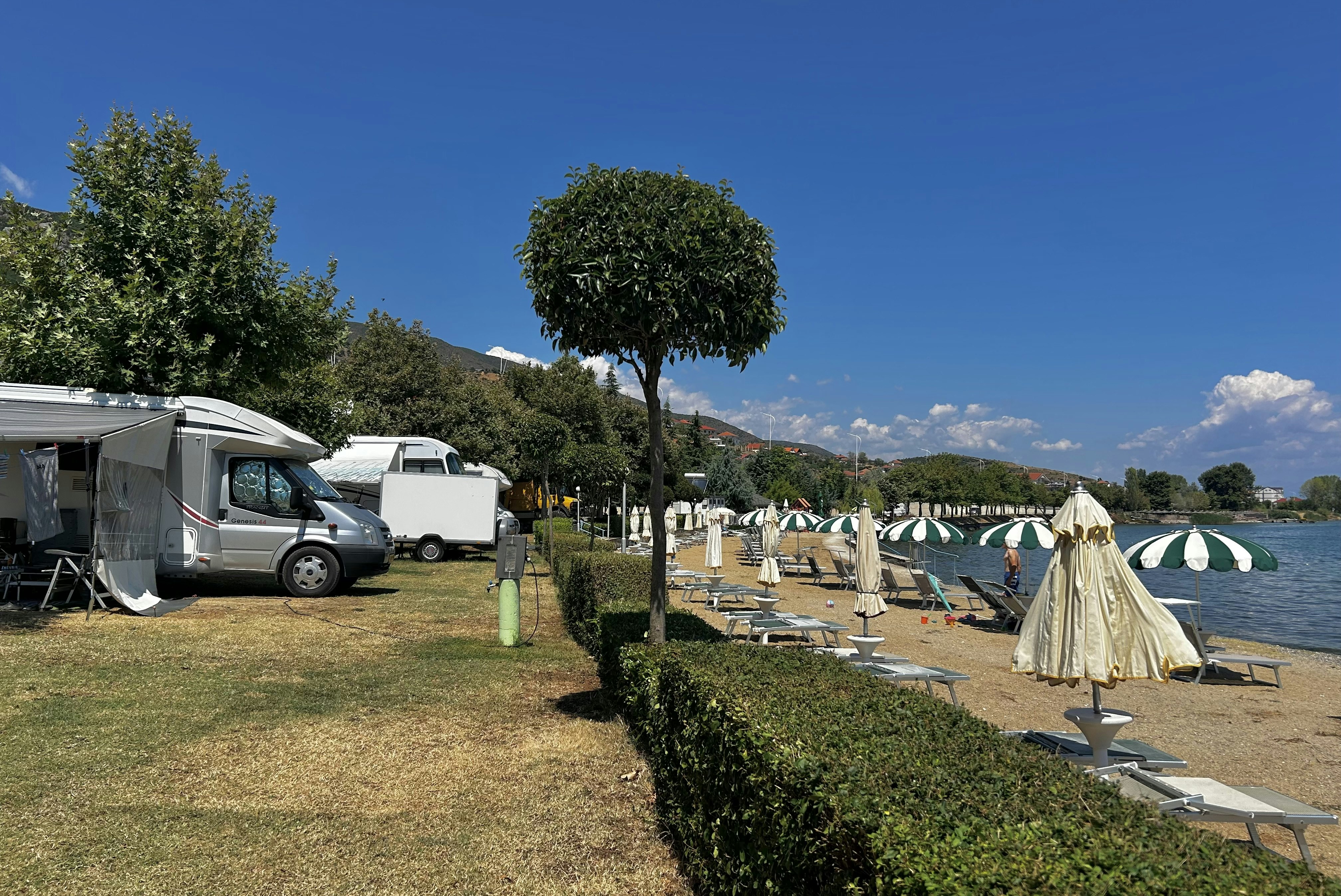 Camping Peshku - Strand mit Liegestühlen und Sonnenschirmen an der Standplatzwiese