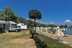 Camping Peshku - Strand mit Liegestühlen und Sonnenschirmen an der Standplatzwiese