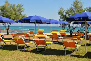 Camping Pilone - Liegestühle und Sonnenschirme auf einer Wiese mit Blick auf das Mittelmeer