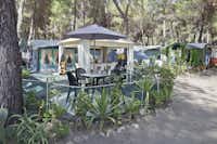 Camping Pineta di Sibari - Wohnwagen mit Vorzelten und eine Terrasse mit Pavillon zwischen Bäumen