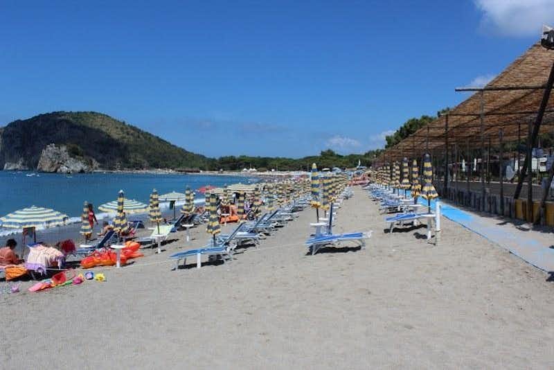 Camping Pineta  -  Strand vom Campingplatz am Mittelmeer mit Sonnenschirmen und Liegestühlen