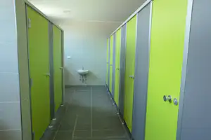 Flur im Camping-Badezimmer mit grünen Türen, grauen Fliesen und Waschbecken in der Mitte.