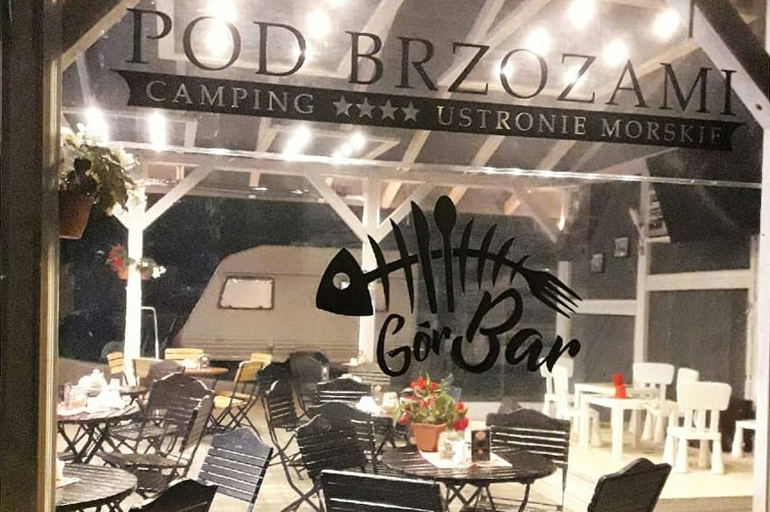 Terrasse mit Campingmöbeln und Tischdekoration unter dem Schild „Pod Brzozami“ am Campingplatz GorBar.