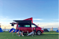 Camping Pole Horyzont -  Camperpaar vor ihrem Wohnwagen in der Sonne
