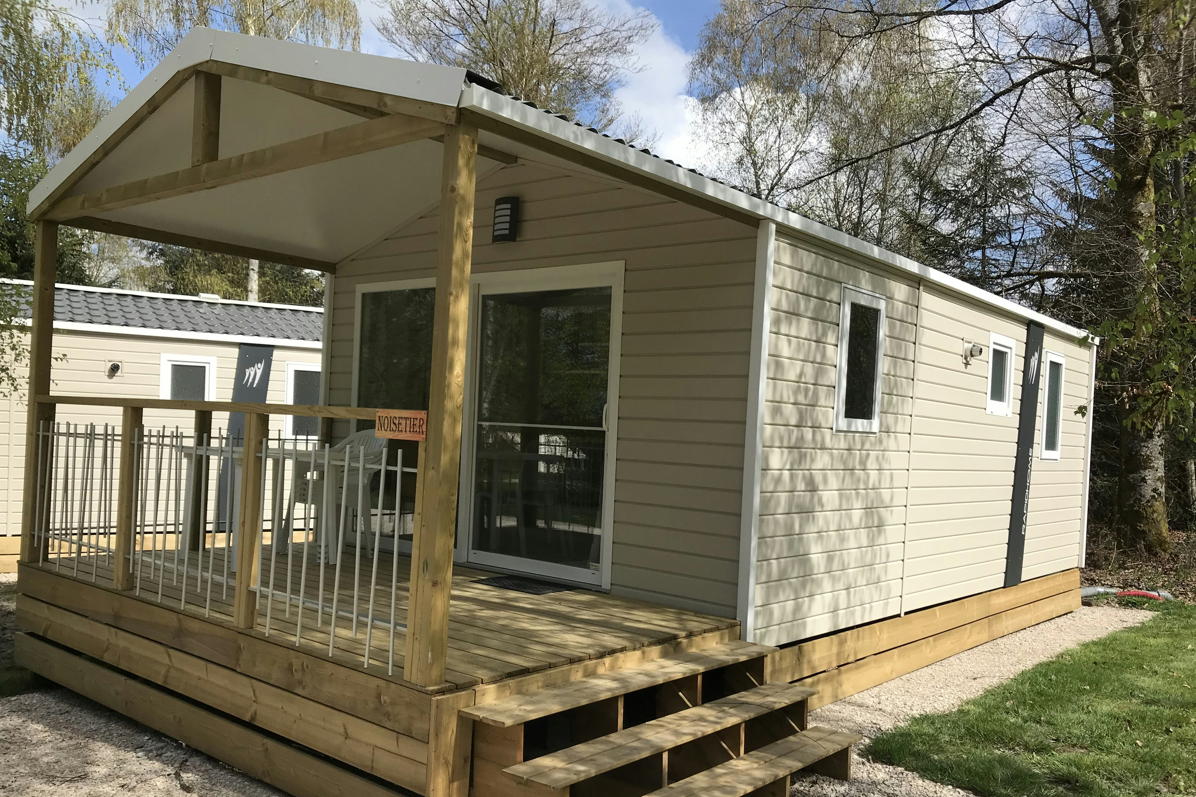 Camping Porte des Vosges - Bungalow mit überdachter Veranda, auf der Sitzgelegenheiten stehen
