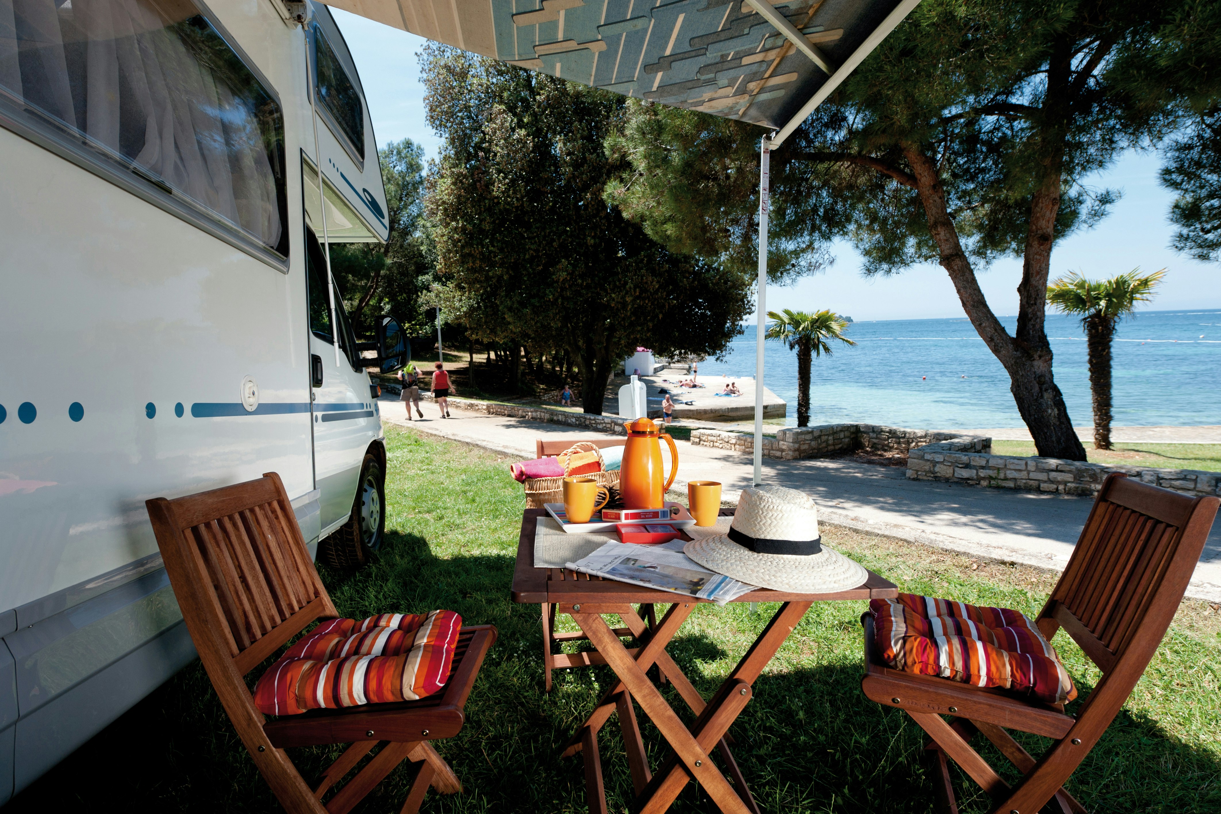 Camping Porto Sole - Sitzgelegenheiten unter der Markise eines Wohnmobils mit dem Mittelmeer im Hintergrund