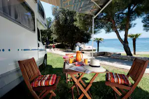 Camping Porto Sole - Sitzgelegenheiten unter der Markise eines Wohnmobils mit dem Mittelmeer im Hintergrund