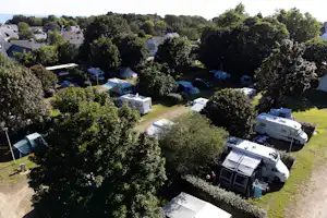 Wohnmobile und Zelte auf einem Campingplatz im Grünen, dazwischen Wege, Bäume und mehrere Stellplätze.